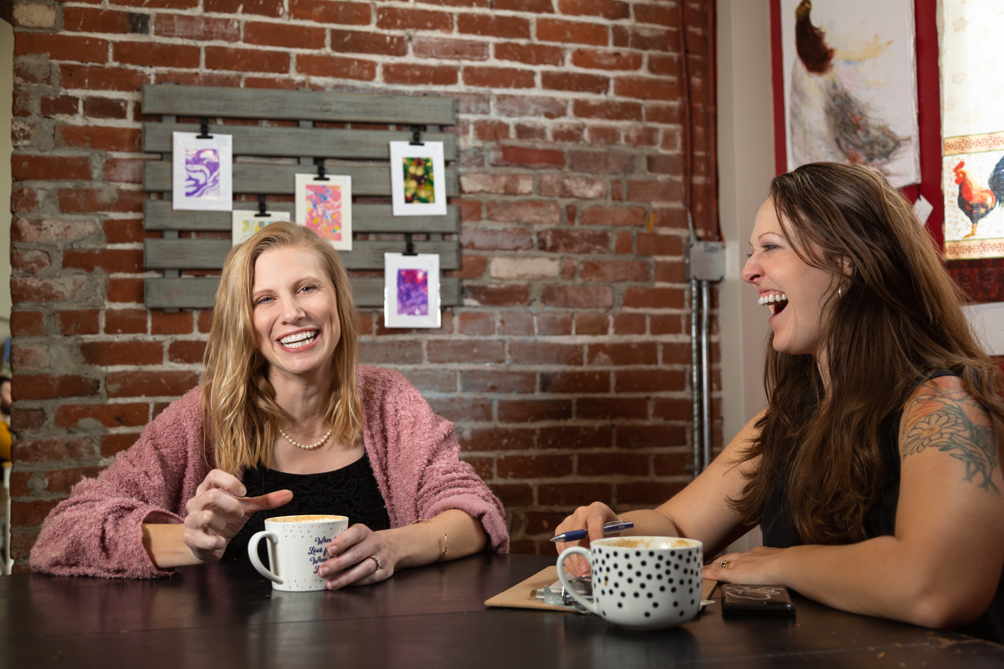 Photo of Danielle Isaac with a client, laughin over cups of coffee