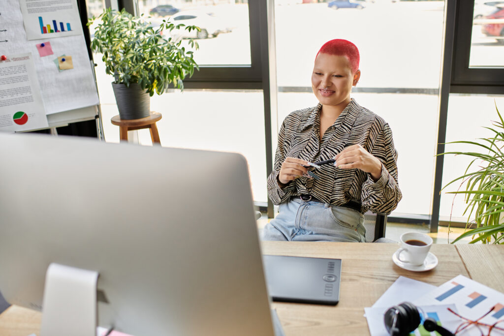 small business owner seated at her computer holding two pens.